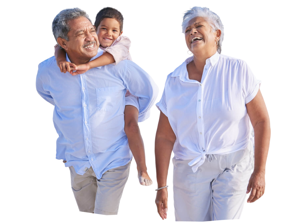 Grandparents walking on sand with child on grandfather’s back