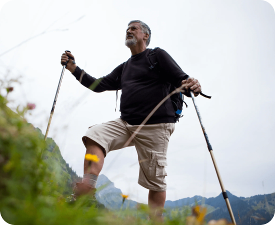 Man hiking uphill with trekking poles outdoors